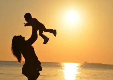 silhouette of a mom holding her child in the air