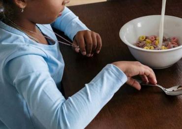 young girl eating cereal at the table