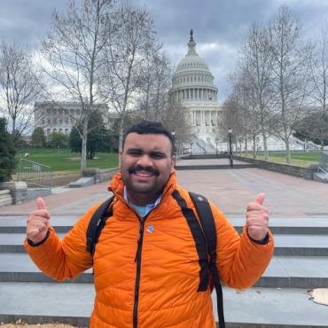 advocate in orange jacket in front of Capitol