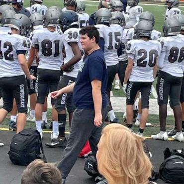 Andrew walking behind a football team