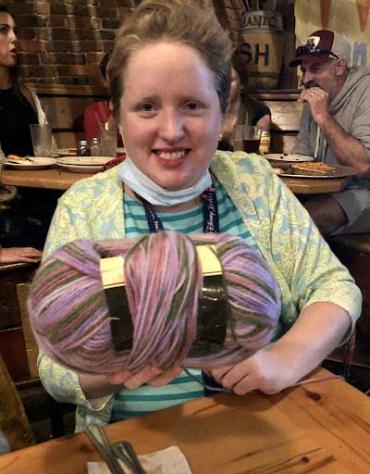 Annie smiling and holding up a ball of yarn