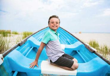 Anthony sitting in a blue kayak on the beach