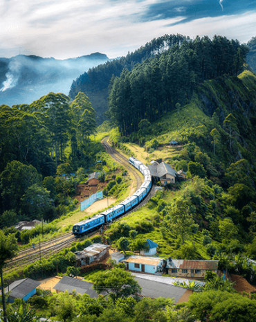 Blue train going down a mountain near houses