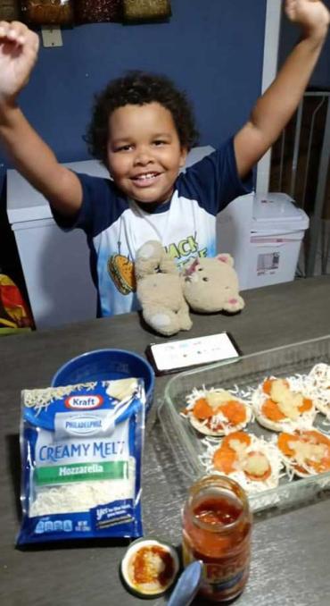 Brandon smiling with his arms in the air after making mini pizzas