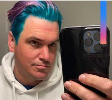 man with purple and blue hair taking a mirror selfie