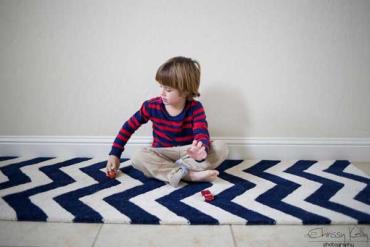 Chrissy Kelly's young son playing with a toy car on the floor