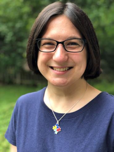 Erin wearing glasses and an autism puzzle piece necklace