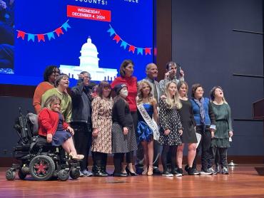 Group of 14 disability advocates standing together on stage