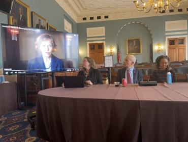 Three panelists watching TV for video of Former First Lady Rosalynn Carter speaking about caregivers