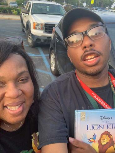 Ira holding a Lion King book with his mom Lisa