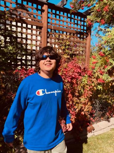 Ishaan wearing a blue sweater and sunglasses outside