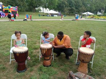 Victoria teaching children to play the drums