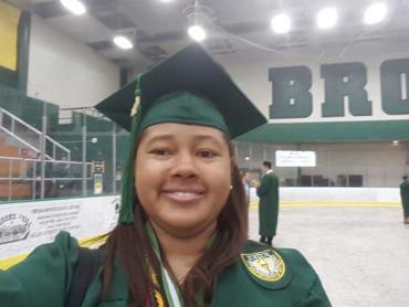 Jessica wearing a green graduation cap and gown