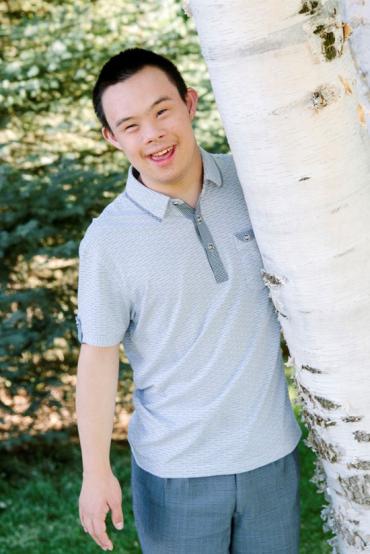 Jonathan smiling standing next to a tree