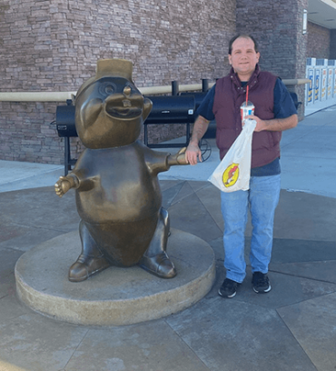 Josh standing next to an otter statue and holding its hand