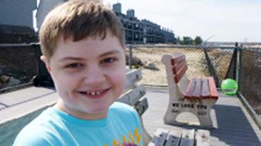 Kimberlee Rutan McCafferty's son sitting on a bench wearing a blue shirt 