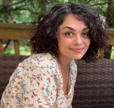 Rose L. wearing a floral shirt and sitting outside smiling