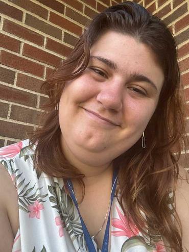 Sarah Robin smiling for a selfie in front of a brick wall