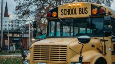 School bus in front of a school in autumn