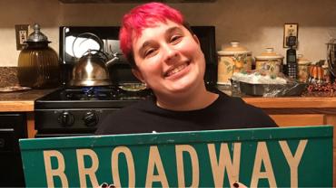 Sophie holding a Broadway street sign