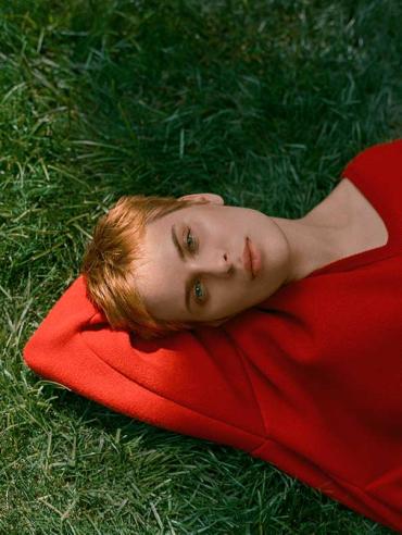 Tallulah Willis wearing a red sweater and laying in the grass