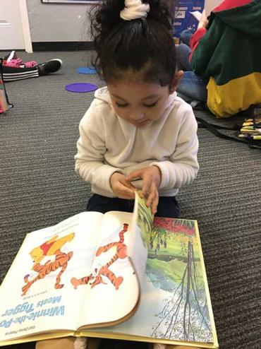 Valeria looking through a Winnie-the-Pooh book