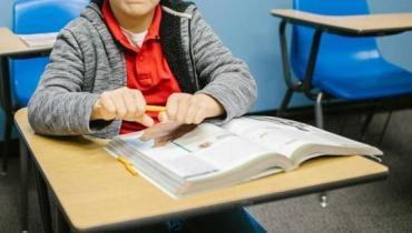 a frustrated child sitting at a desk trying to snap a pencil in half