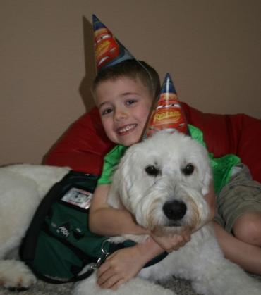 a young boy and his service dog wearing birthday hats