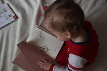 aerial view of a little boy reading a book in bed