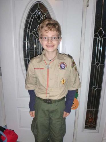 boy with blonde hair and glasses wearing a Boy Scout uniform