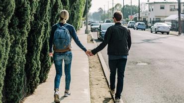 2 adults walking down the street holding hands