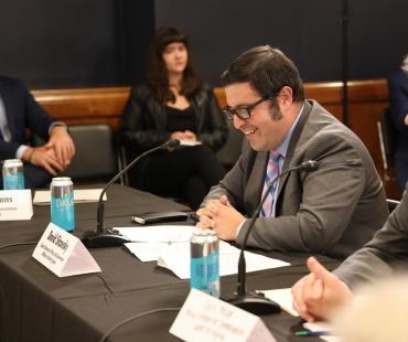 Dave Sitscovsky sitting at black table smiling and speaking into microphone