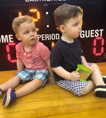 fraternal twins Callan and Brennan sitting in front of a scoreboard