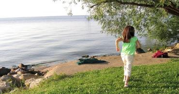 child in a green shirt near a body of water