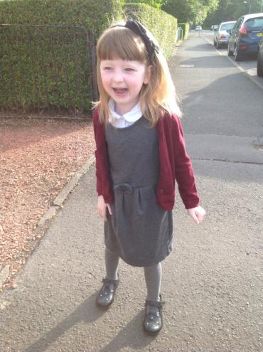 little girl wearing a dress and red cardigan with a bow in her hair