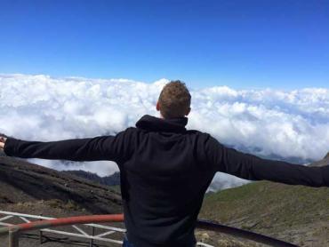 man on a mountain top looking at the clouds