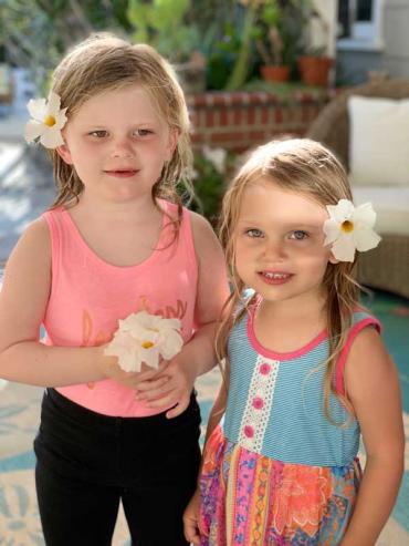 sisters ella and tonya with flowers behind their ears