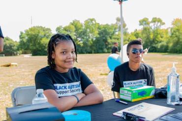 two children sitting at a table during a Black Autism Support Society event