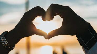 two people putting their hands together to make a heart shape