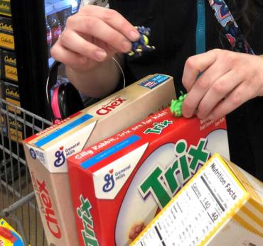 someone waiting in line at grocery store playing with figurines on cereal boxes