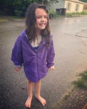 little girl in the rain with a purple rain coat